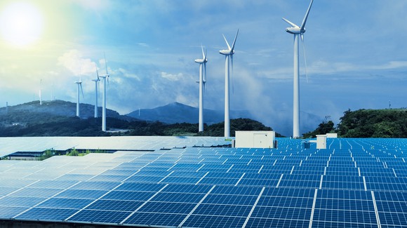 Solar and wind farm with a setting sun on the horizon. 