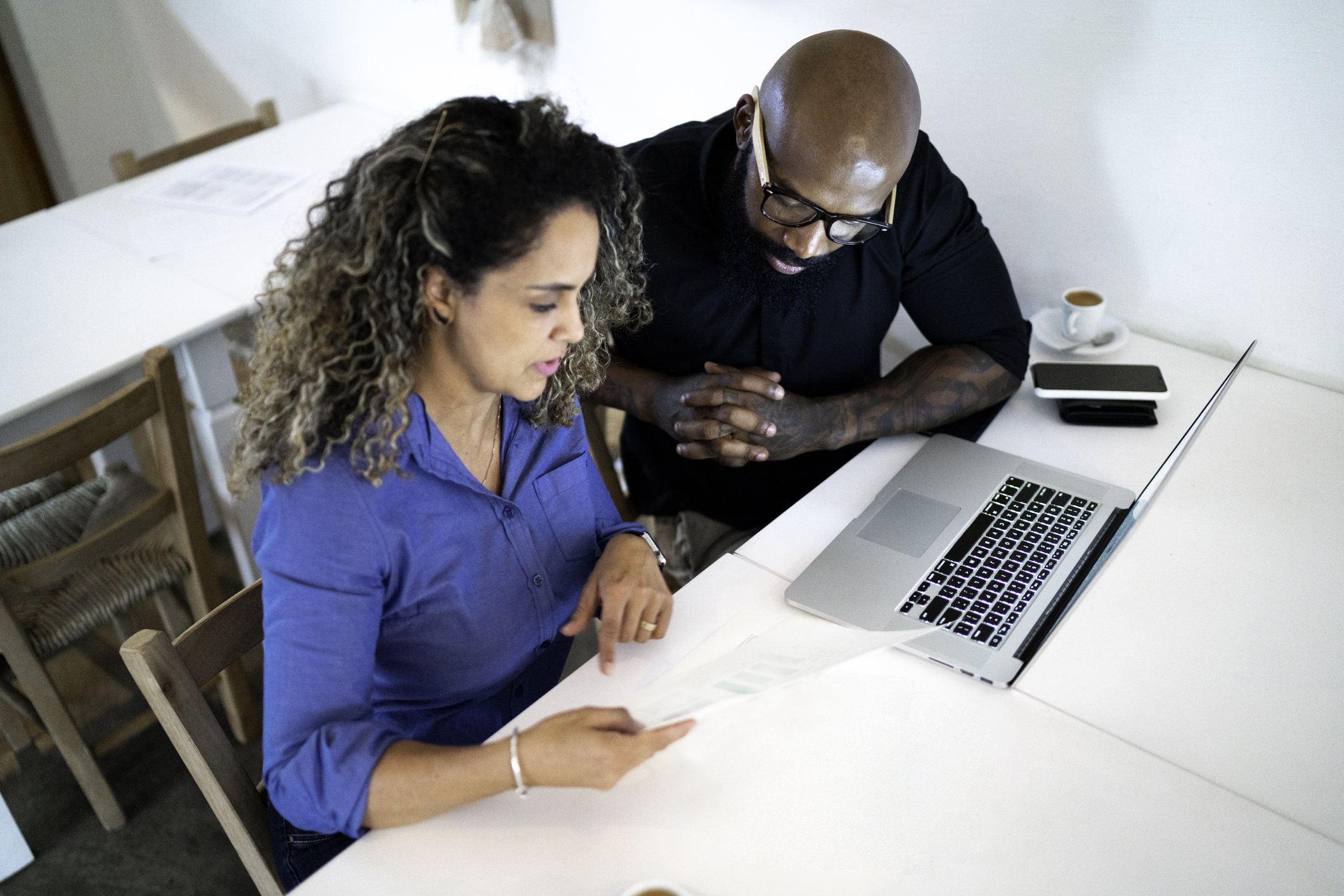 two coworkers ponder papers at desk
