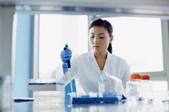 A scientist using a pipette at a lab bench.