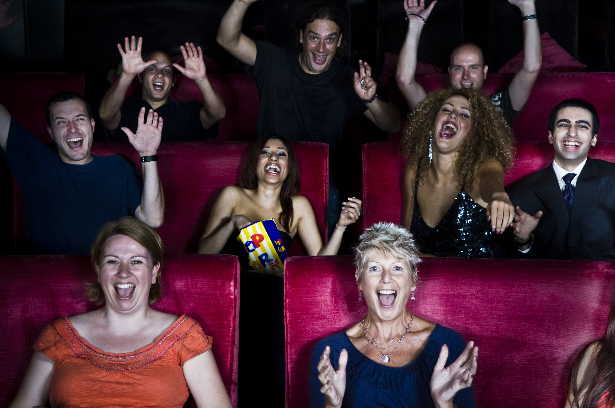 A crowd of people in a movie theater appear excited.