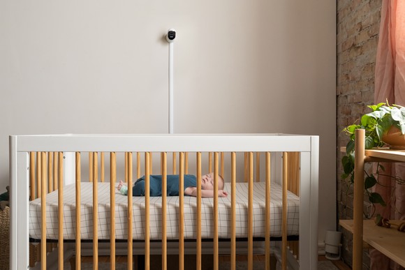 Baby lying in crib and wearing Owlet socks with monitor overhead. 
