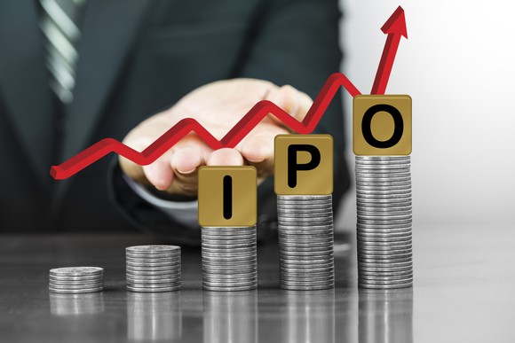 A stack of coins growing with tiles with the letters I, P, and O.