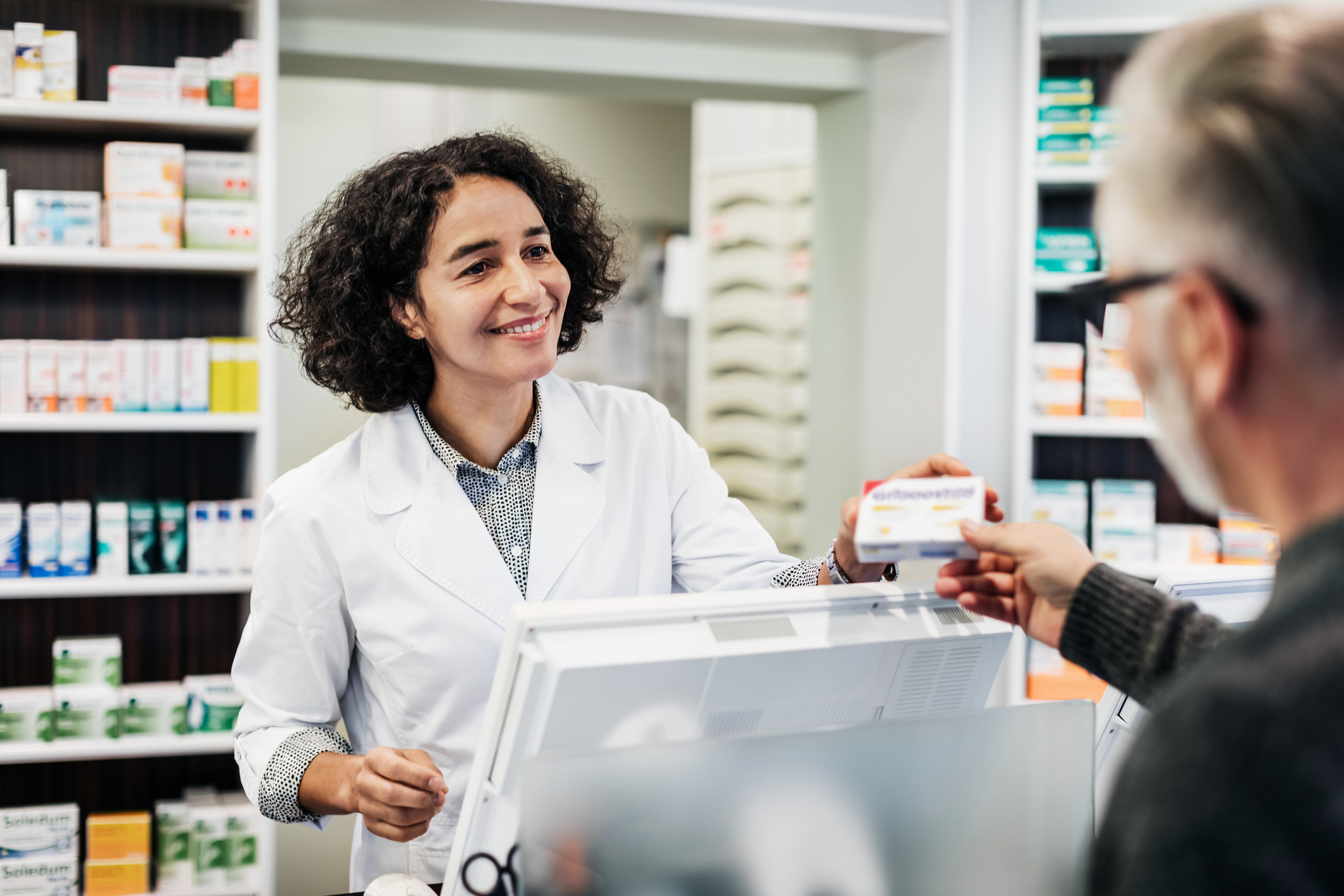 Pharmacist handing prescription to a customer.