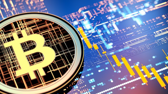 Bitcoin logo with falling charts in the background. 