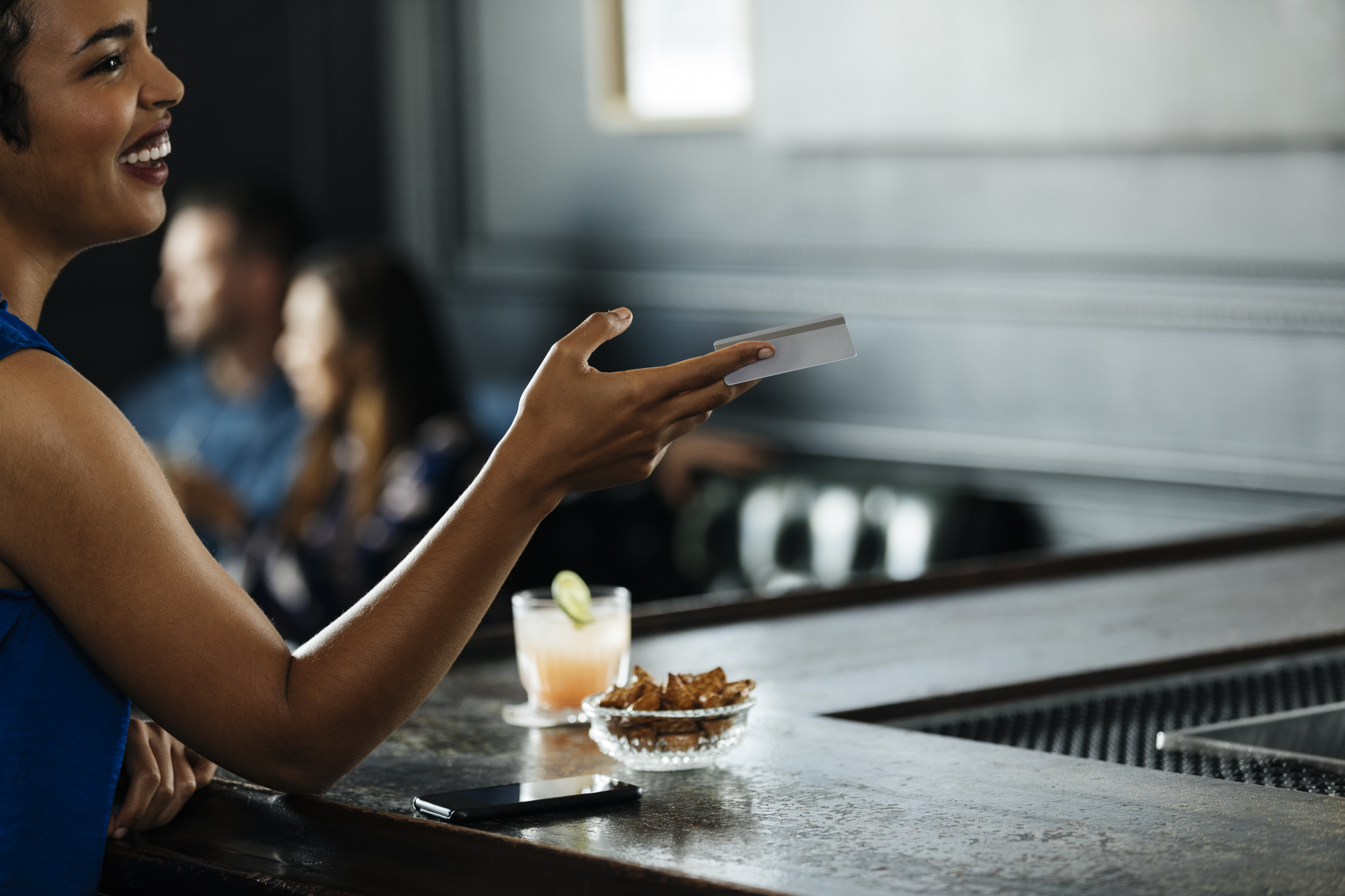Woman handing her credit card to a bartender.