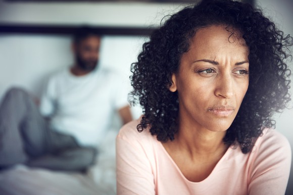 Upset person in foreground and person on couch in background.