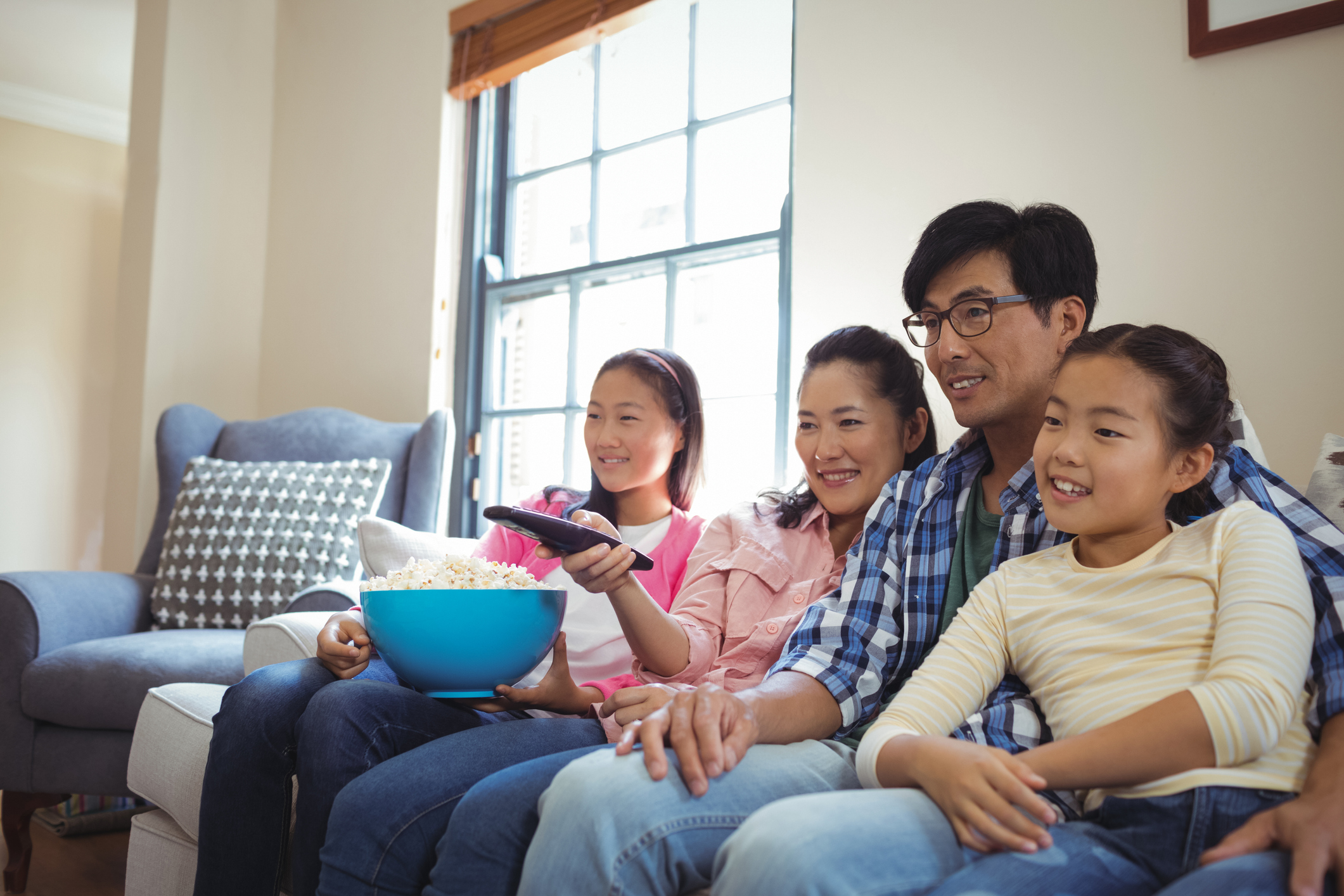 A family sitting on the couch and watching television.