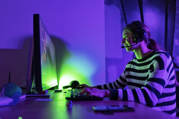 A teenager playing video games on a desktop computer.