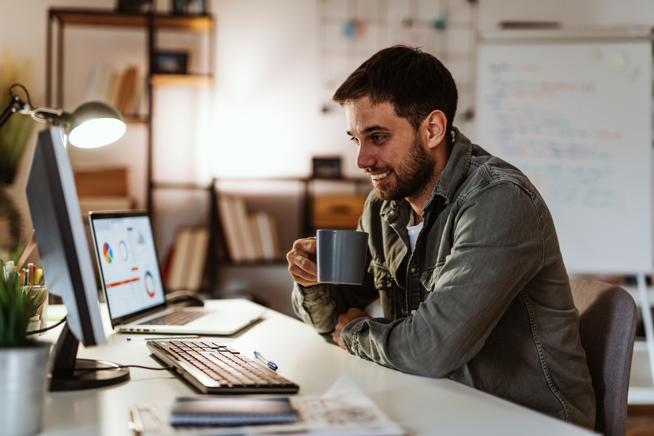 Person viewing finances on computer screens in home office.