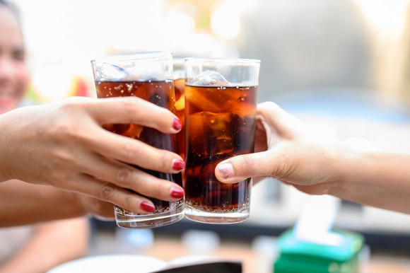 A group of people clinking their glasses of soda.