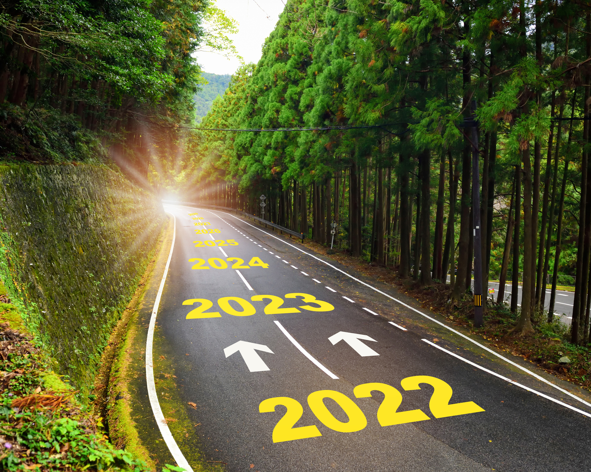 Road marked with years ahead 2022 2023, etc., leading toward sunlight.
