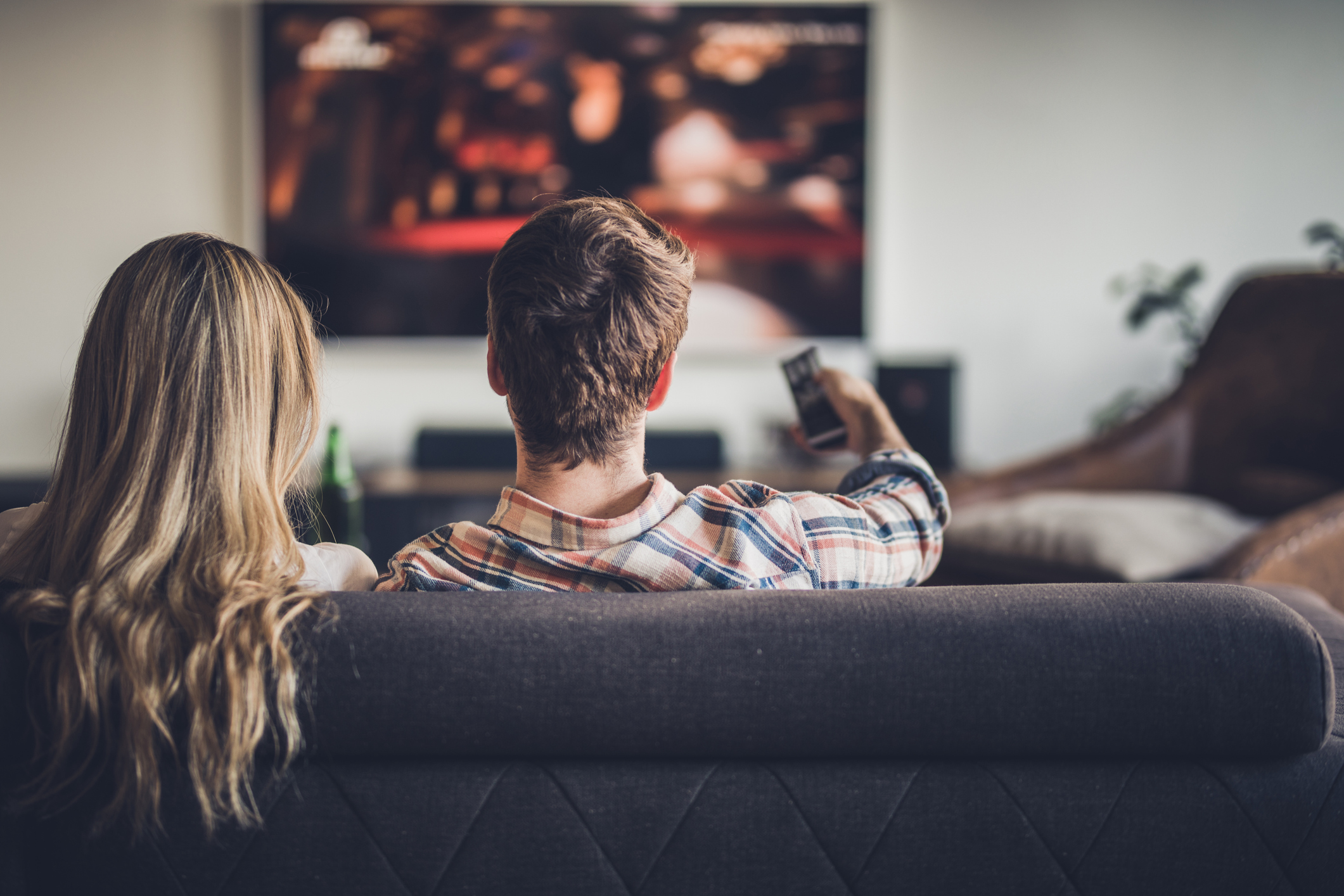 Two people on their couch watching television.