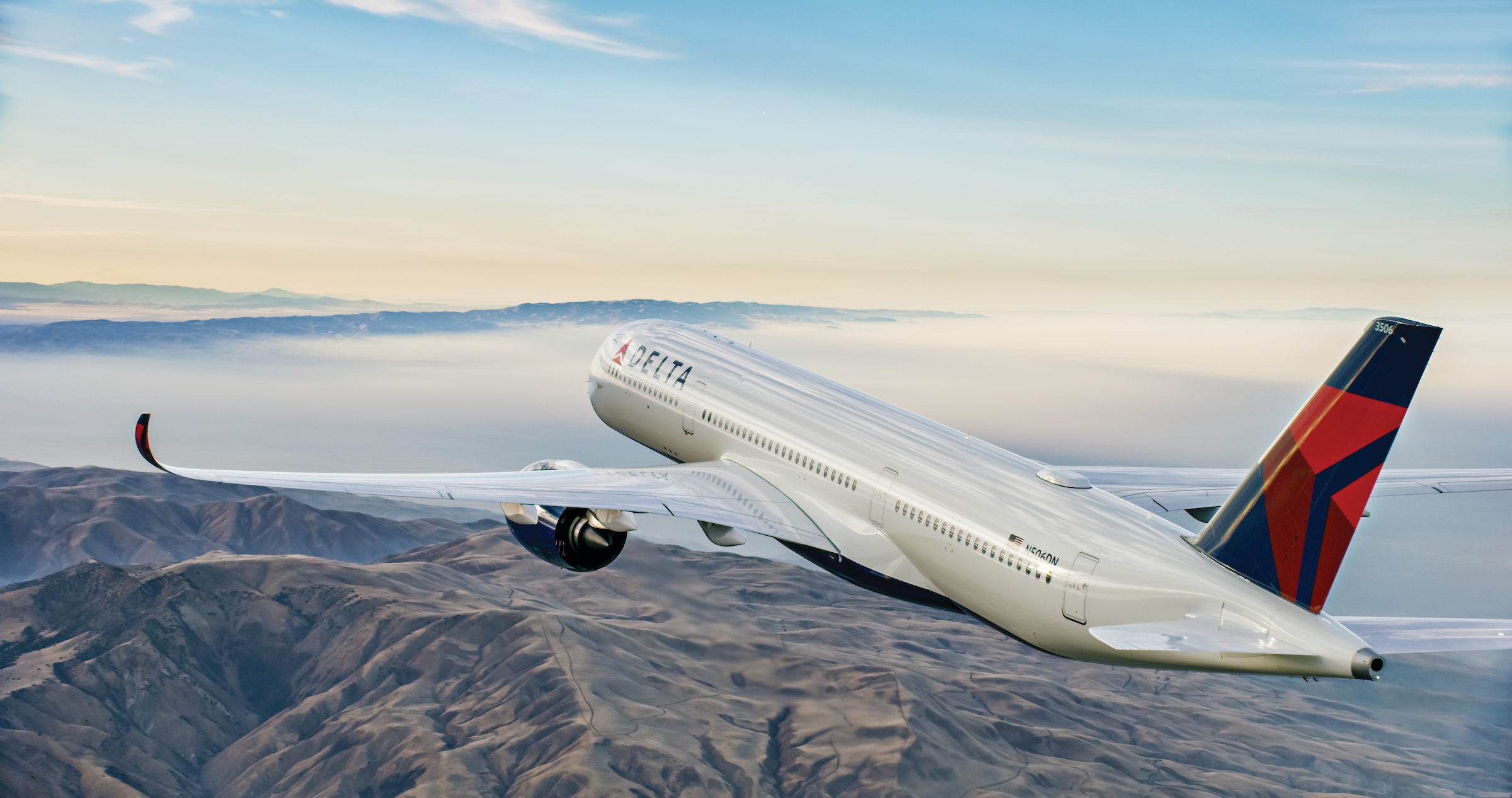 A rear view of a Delta Air Lines plane flying near a coastline.