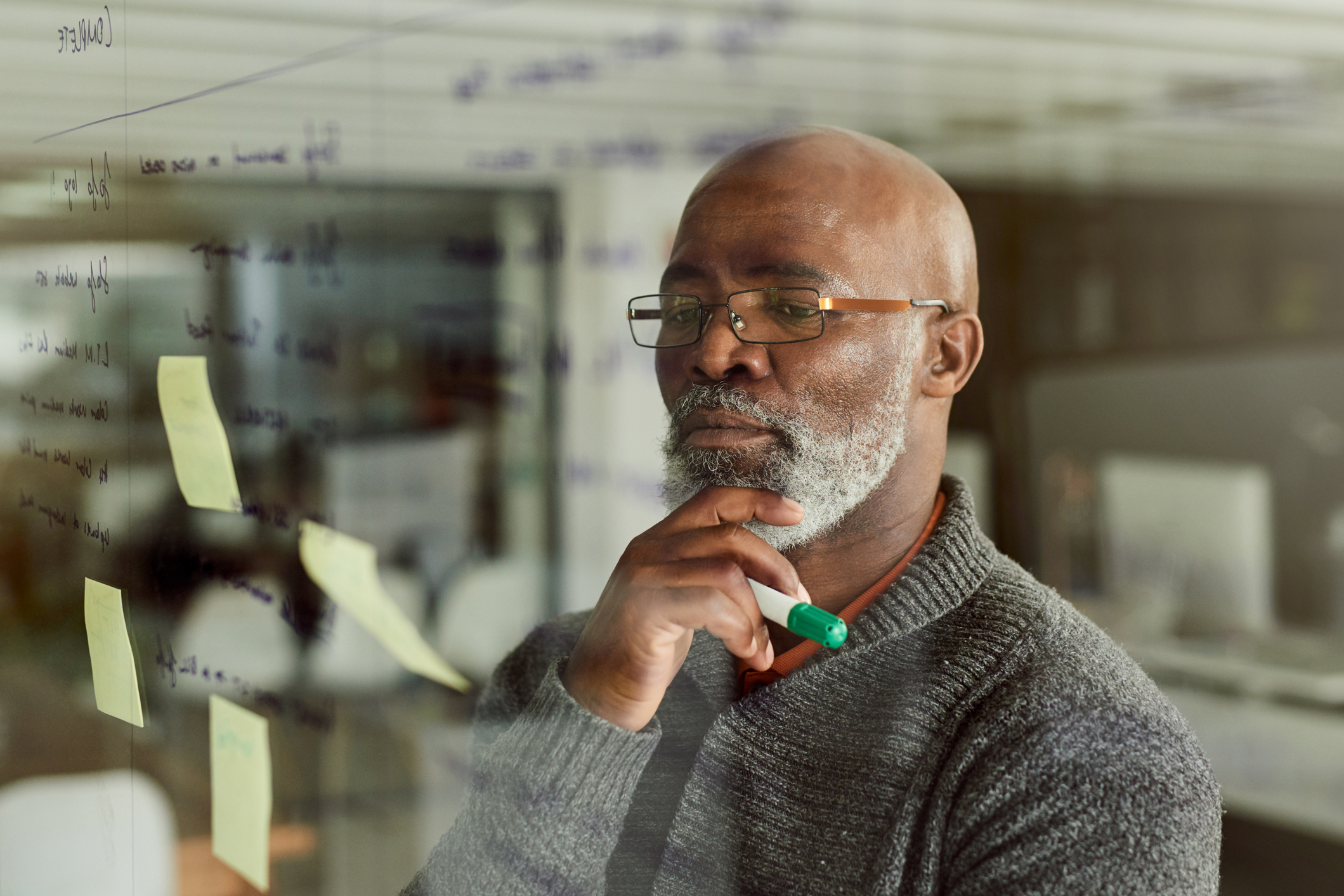 person looking at a clear whiteboard, thinking.