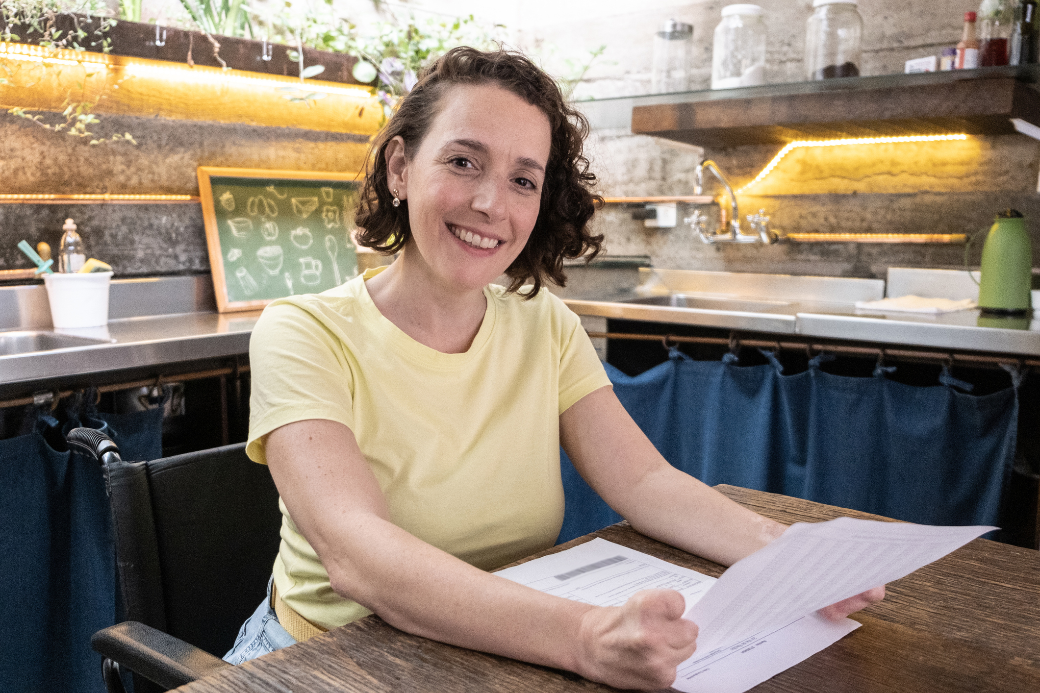 A happy person at a desk, holding papers.