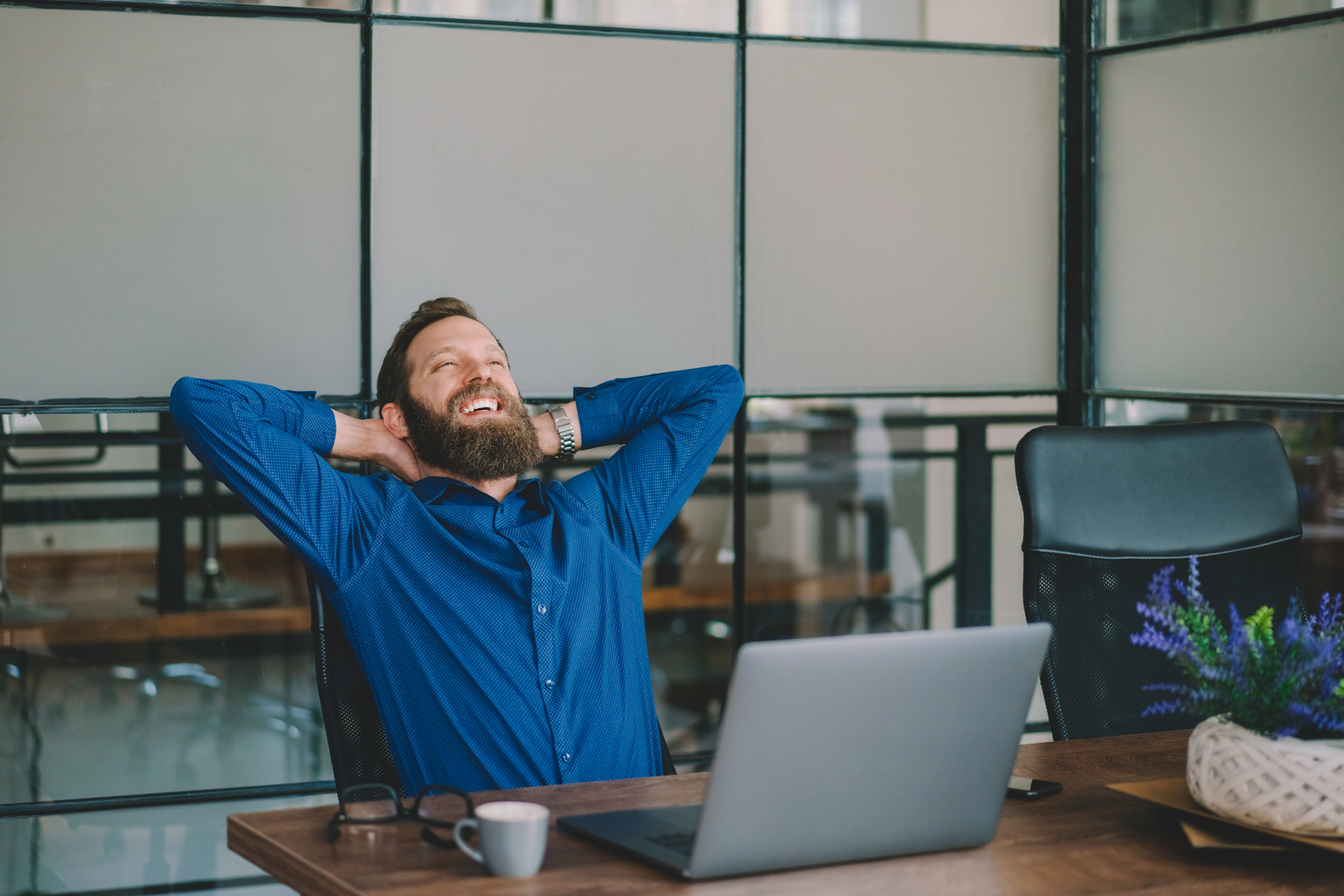 A man smiles while working on a laptop.