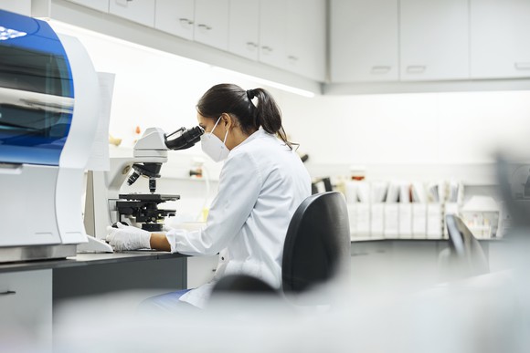 Person in lab looking through a microscope.