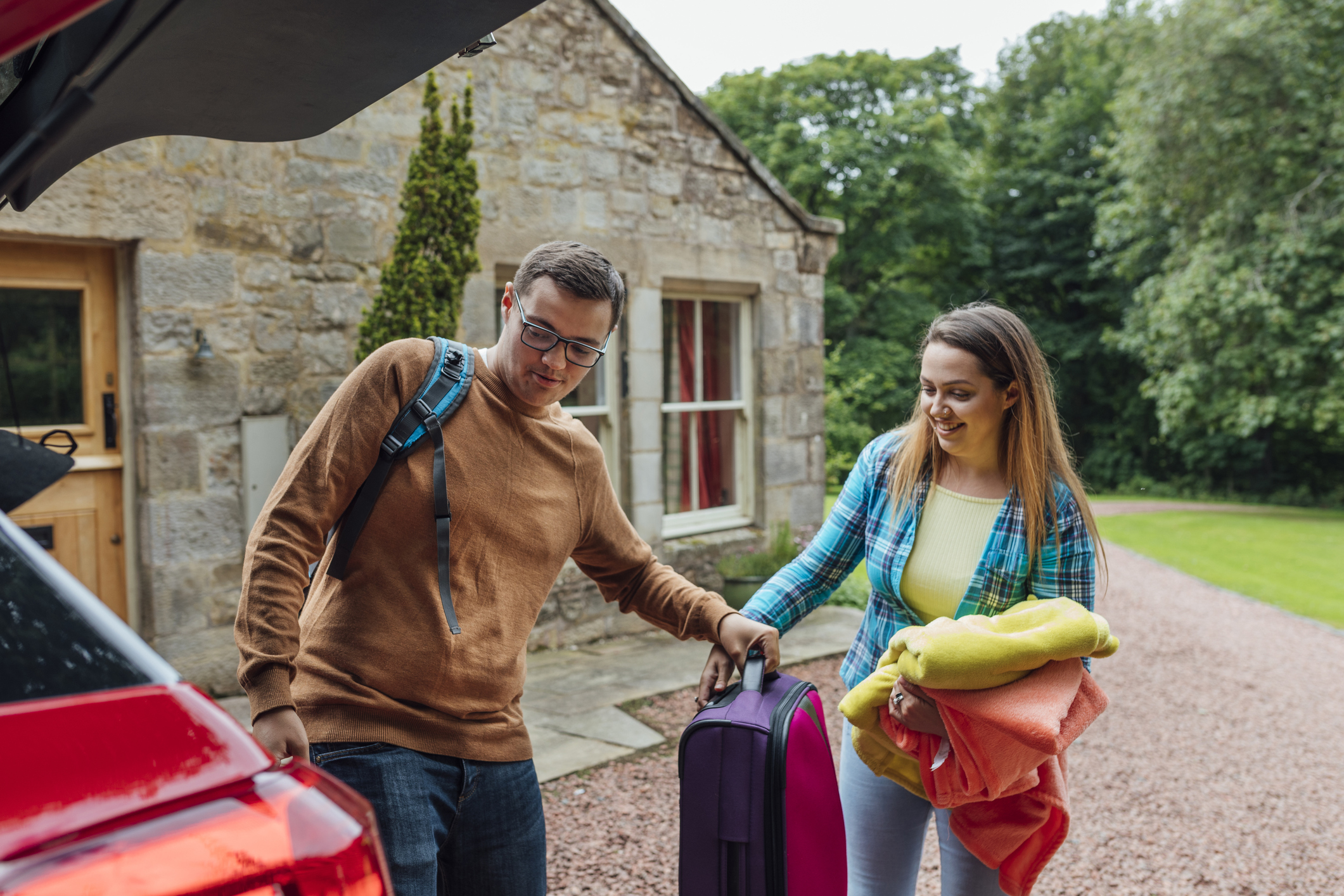 A couple unpacking luggage from their car.