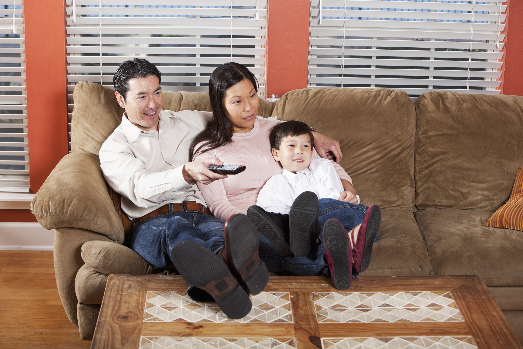 A family sitting on the couch and watching television.
