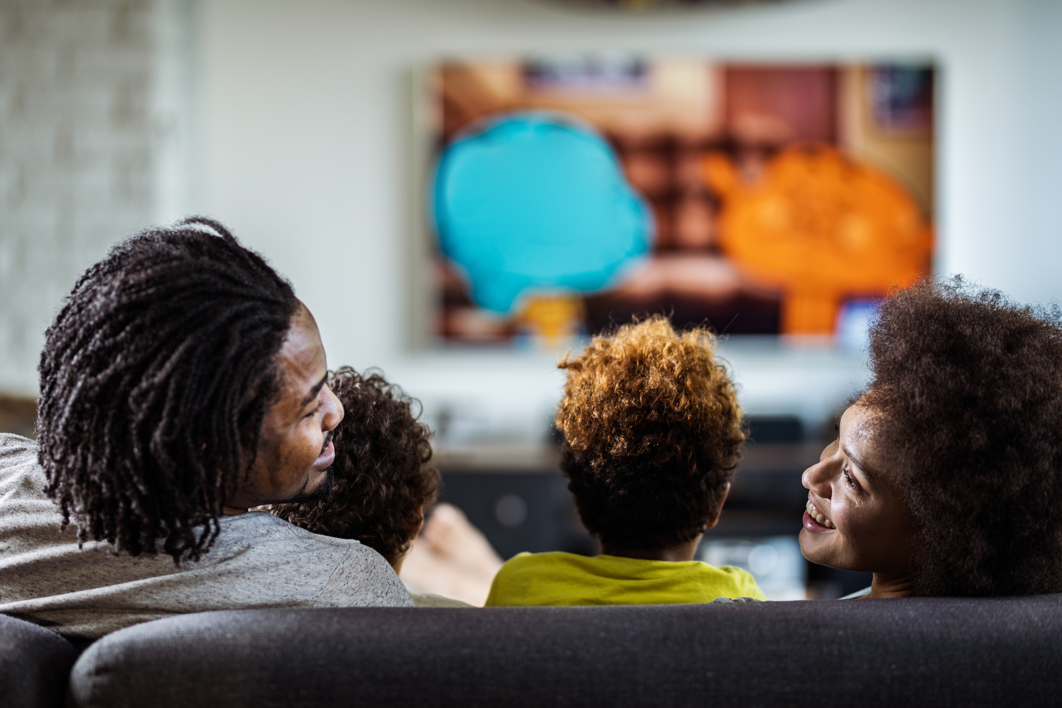 A family of four watching television at home.