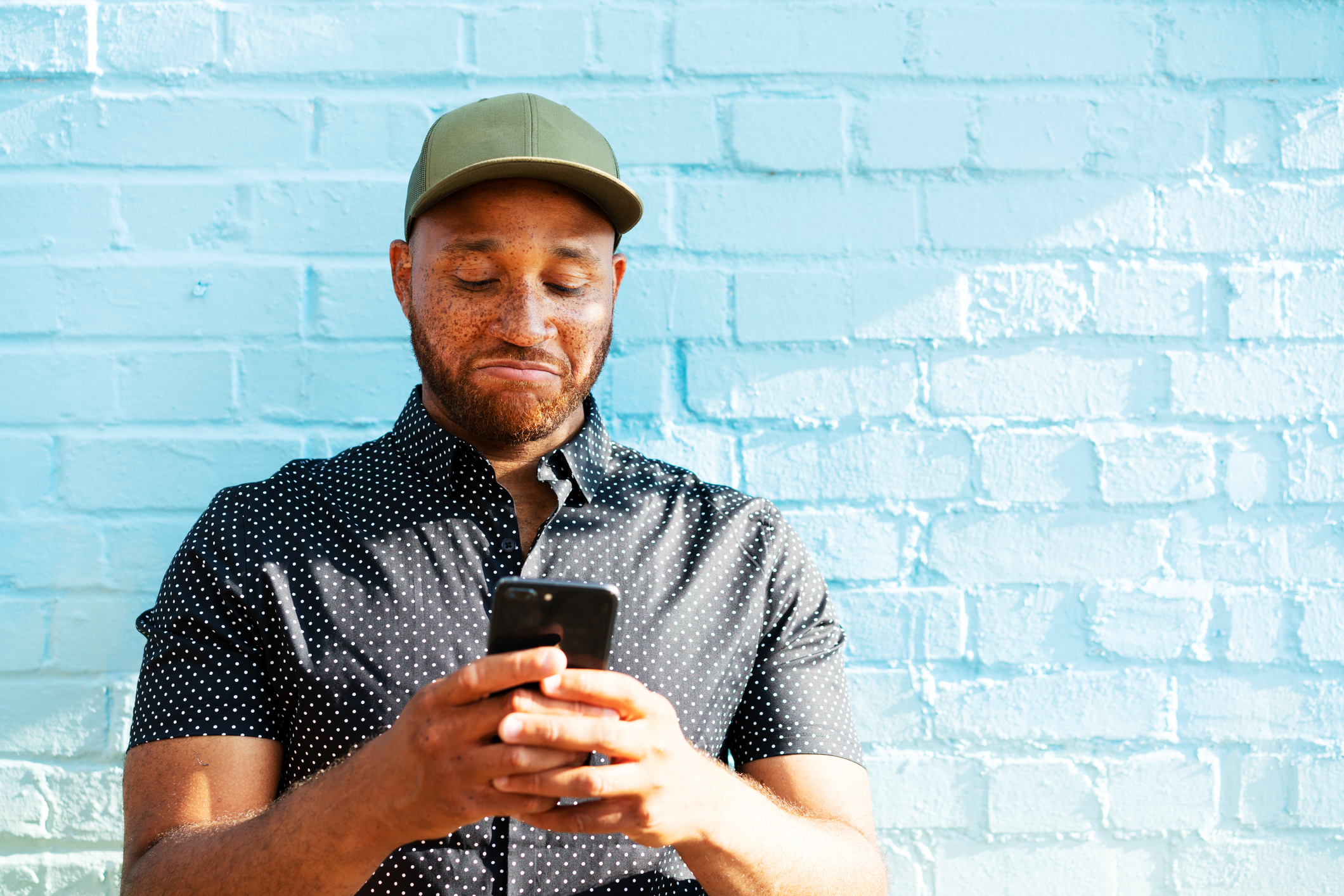A frowning person looks at a smartphone.