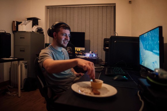 Person sitting in front of computer and eating.