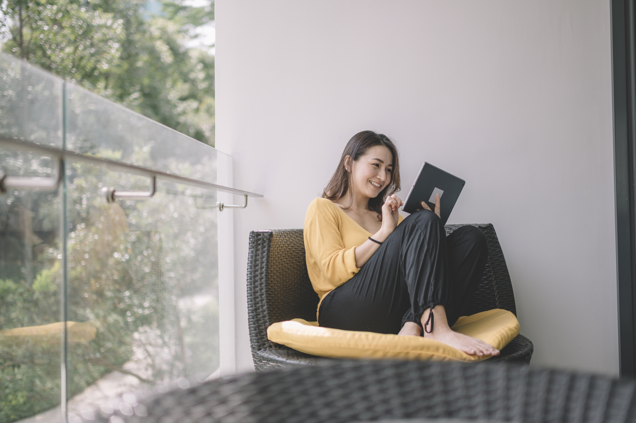 A person looking at their tablet on an outdoor balcony.