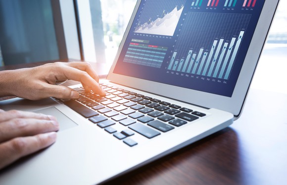 A person looking at charts on a laptop.