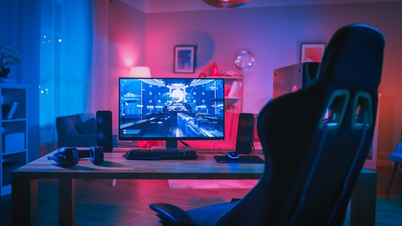 An empty chair is in front of a computer gaming system. 