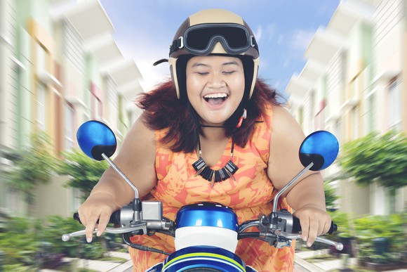 A person is smiling broadly, riding a motorcycle.