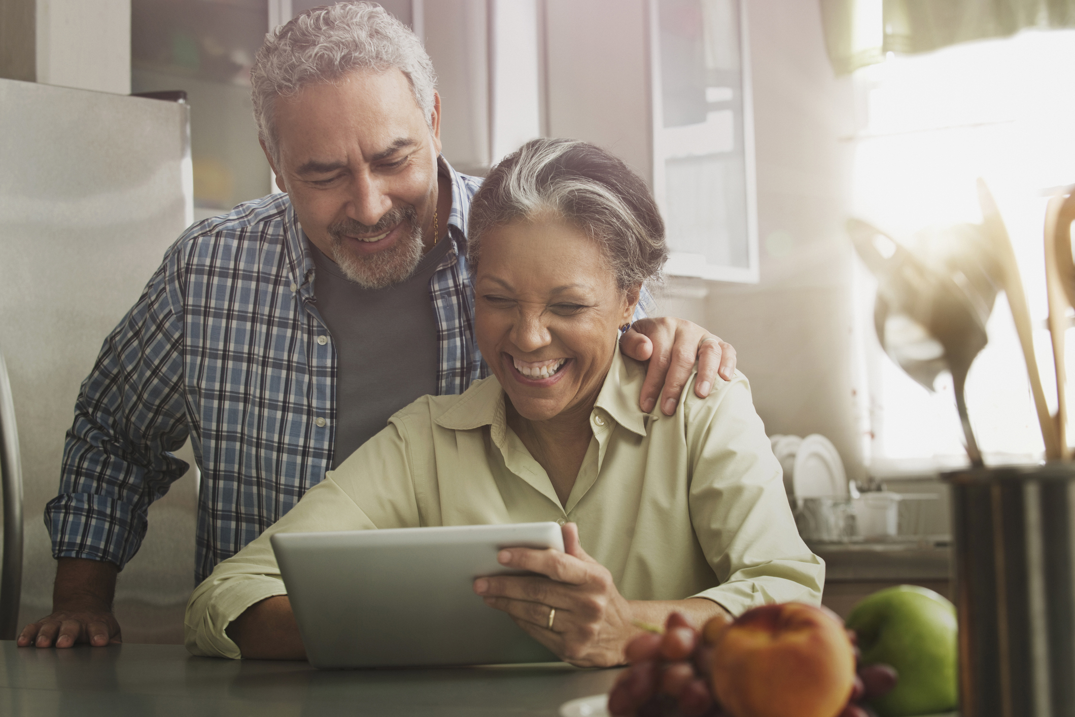 Two smiling people looking at a touchscreen tablet.