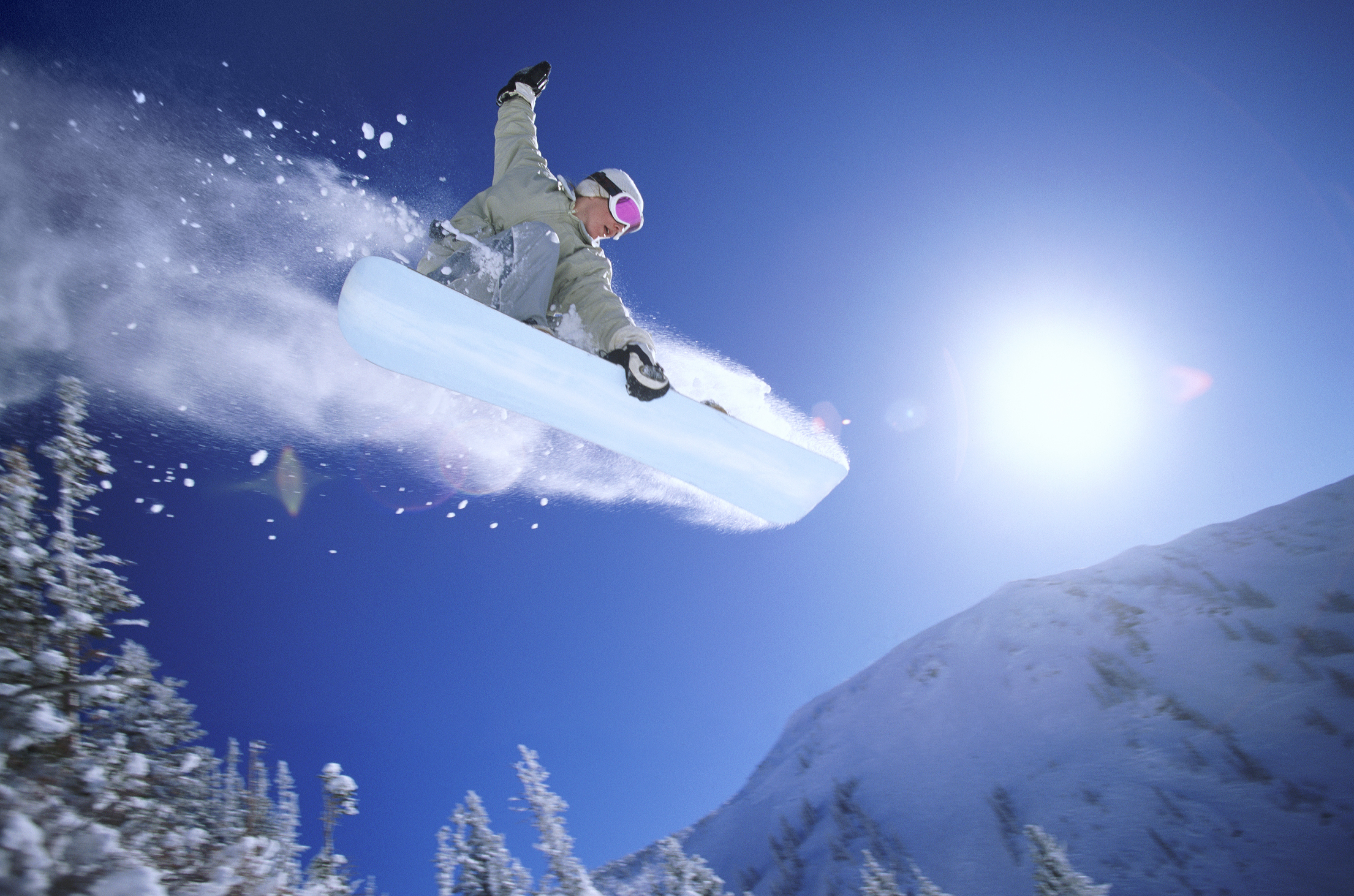 A low-angle view of a person snowboarding in midair.