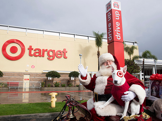 Santa Claus and a dog sitting in a sleigh outside of a Target.