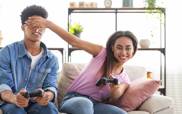 Teenage couple horsing around while playing a video game.
