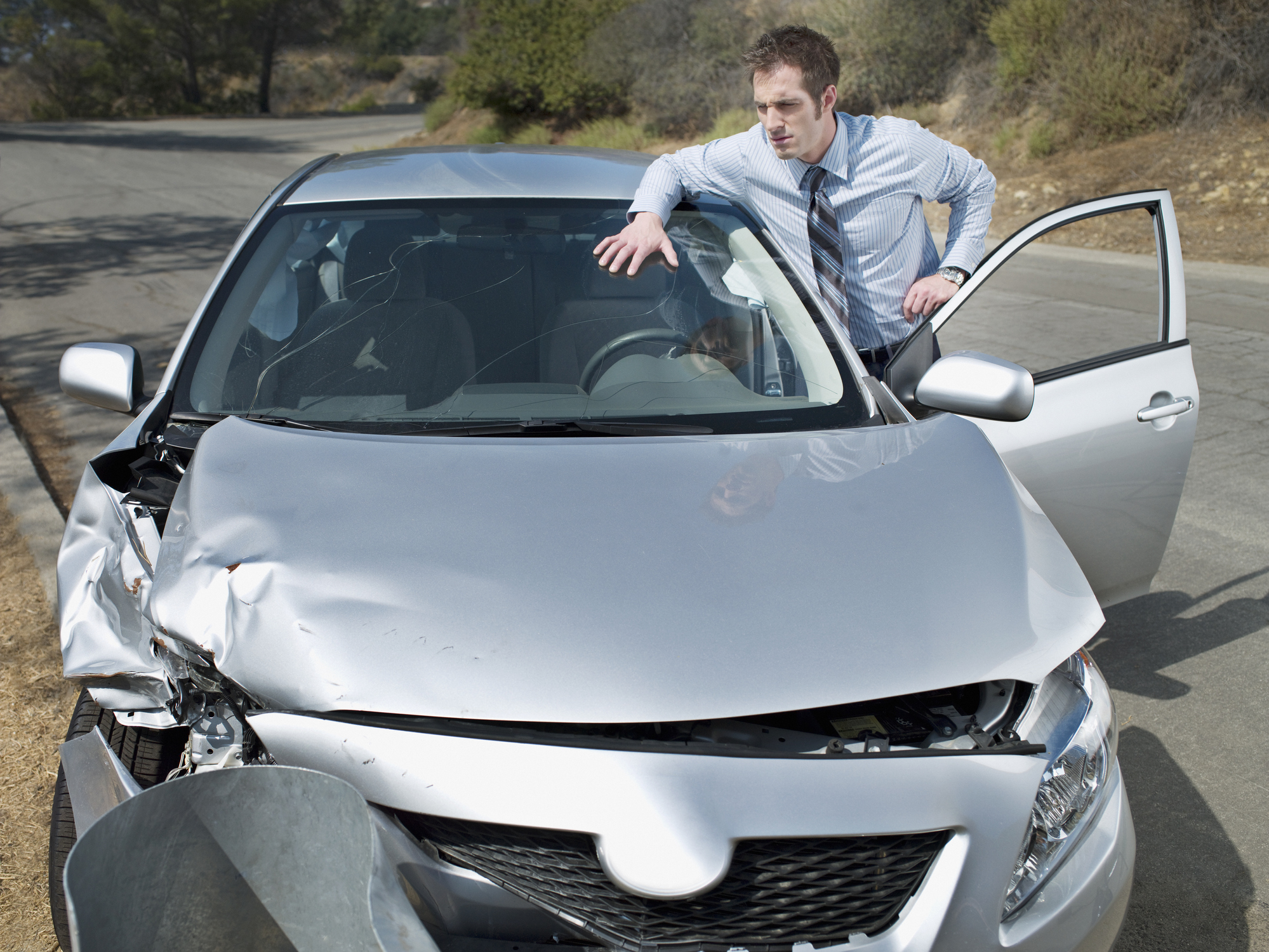 Person looking at their crashed car.