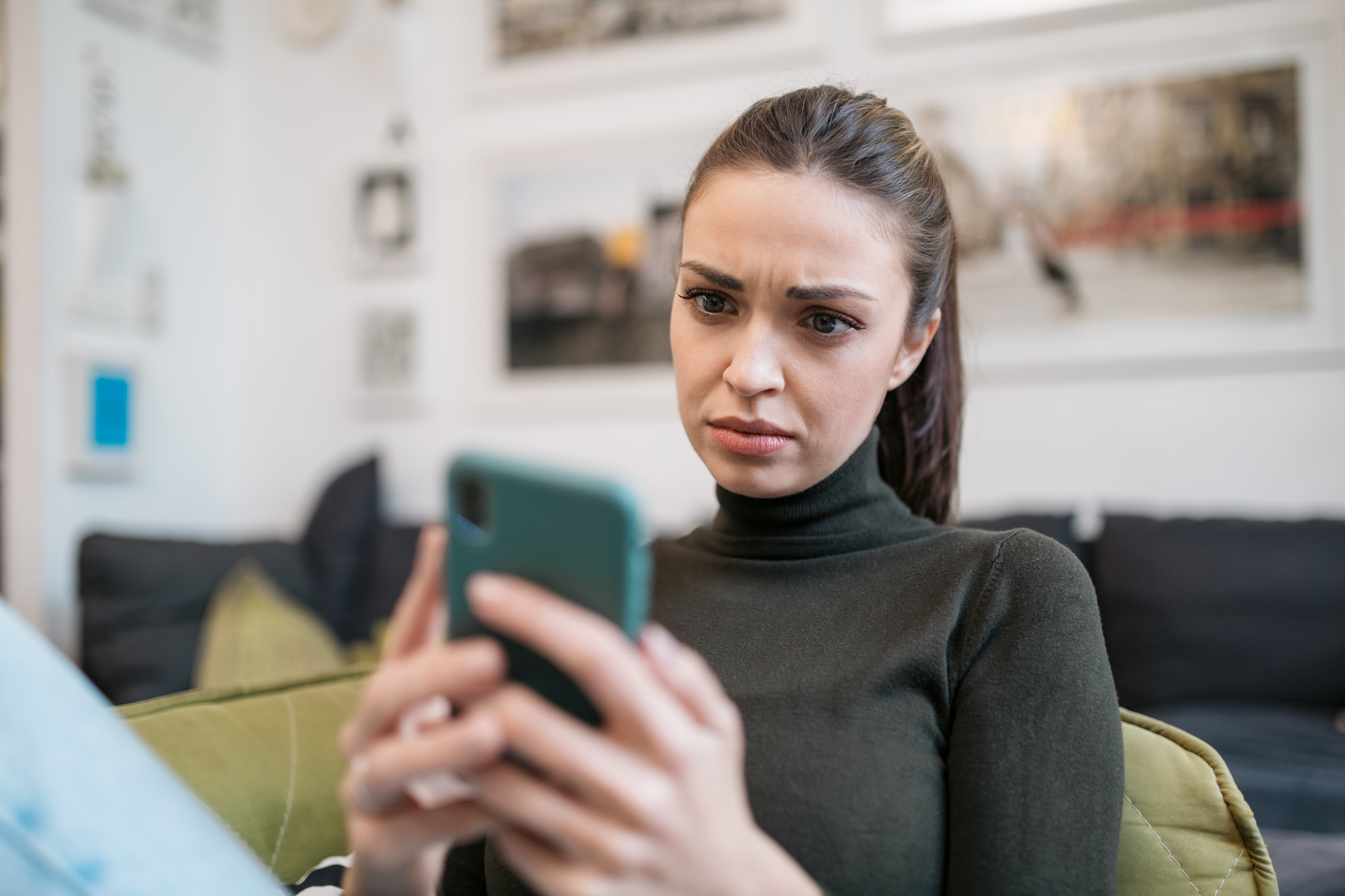A person using a smartphone and looking upset and confused.