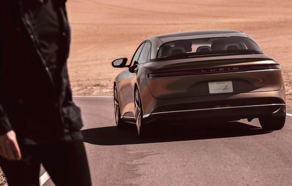 A lucid air driving on a highway through the desert. 