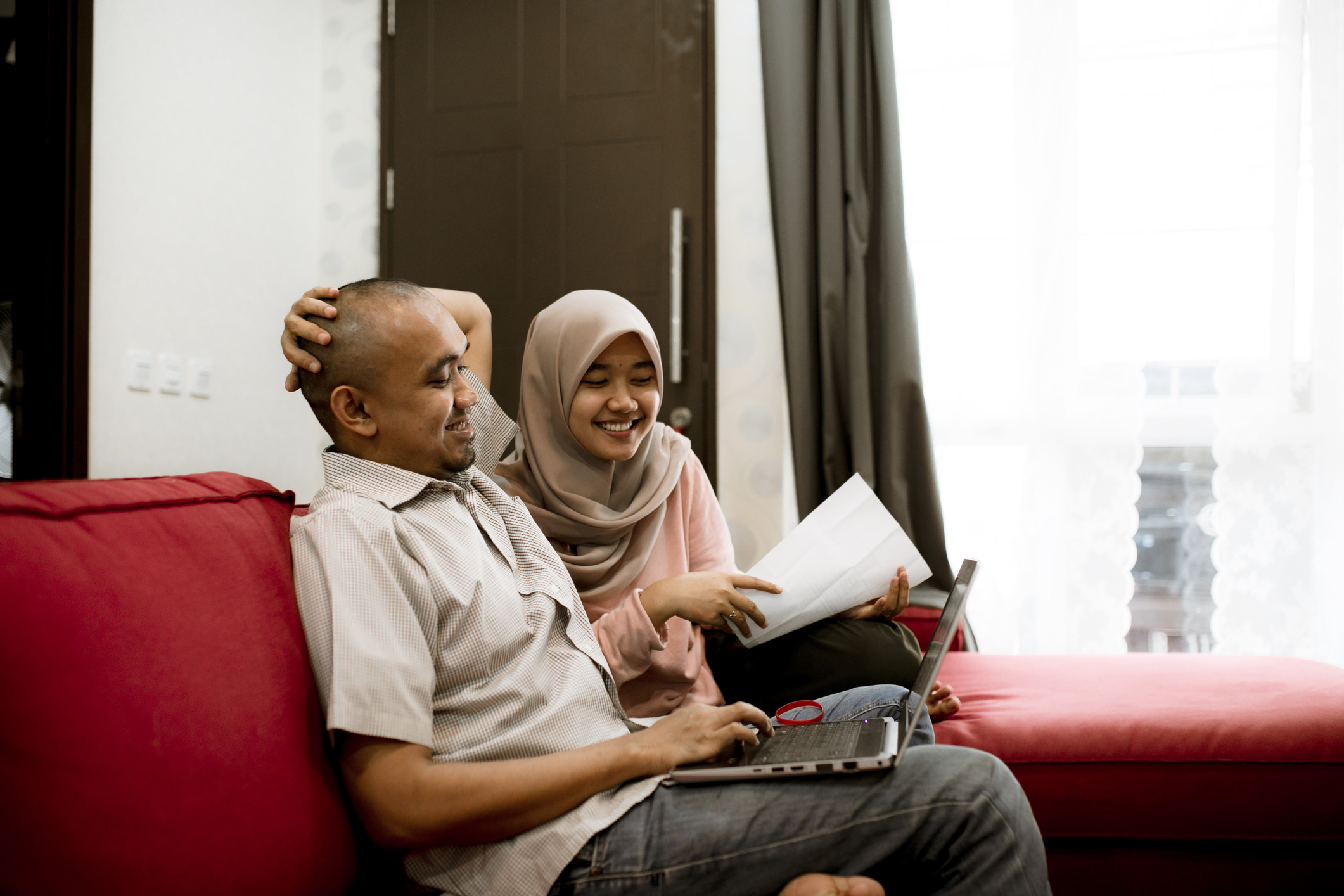 Two people sit next to each other looking at a laptop.