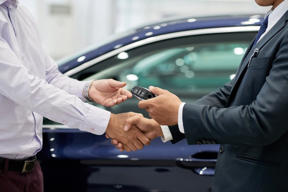 People shaking hands while one hands car keys to the other.