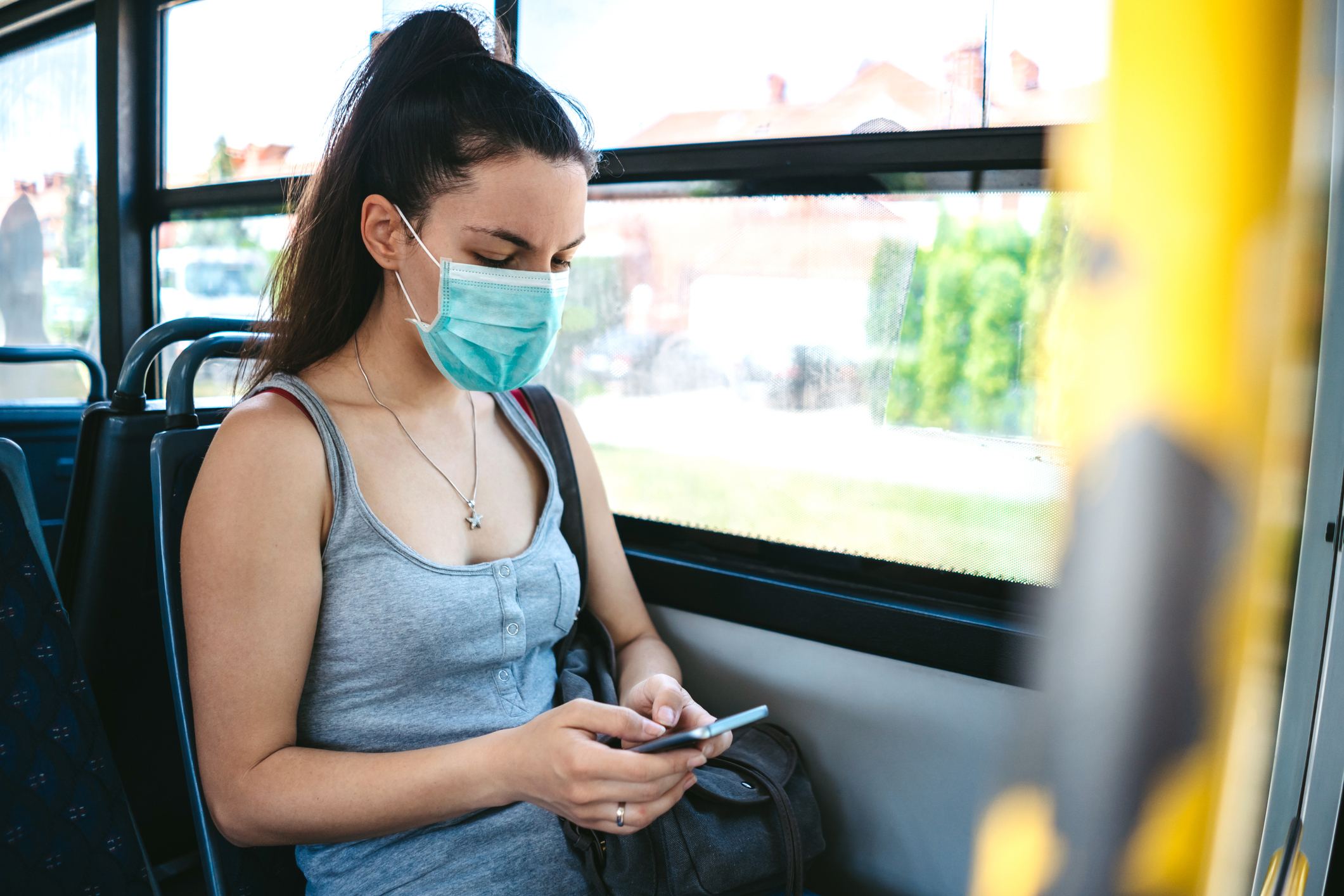 Person wearing a surgical mask while riding a bus.