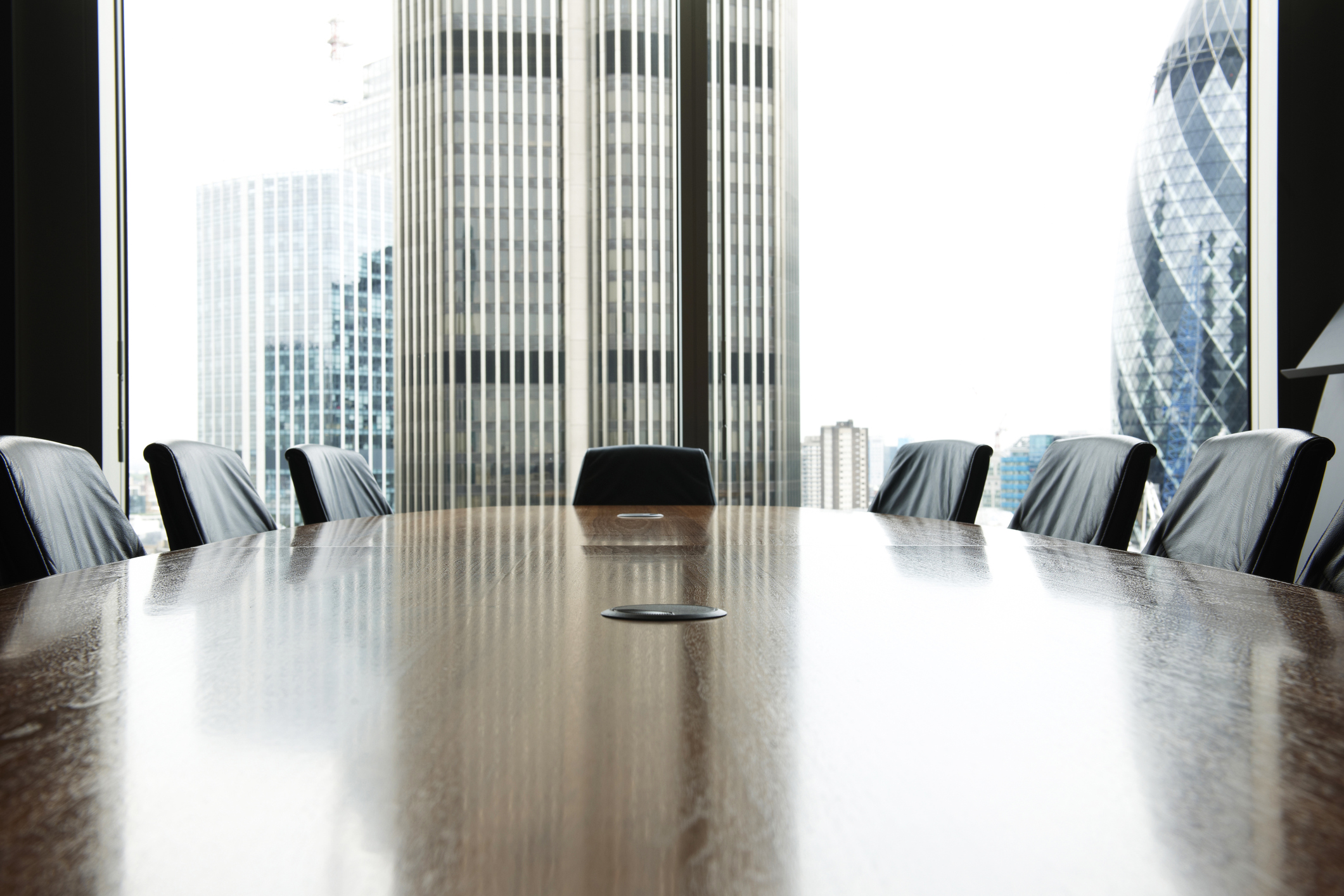 A table and chairs are in an empty boardroom.