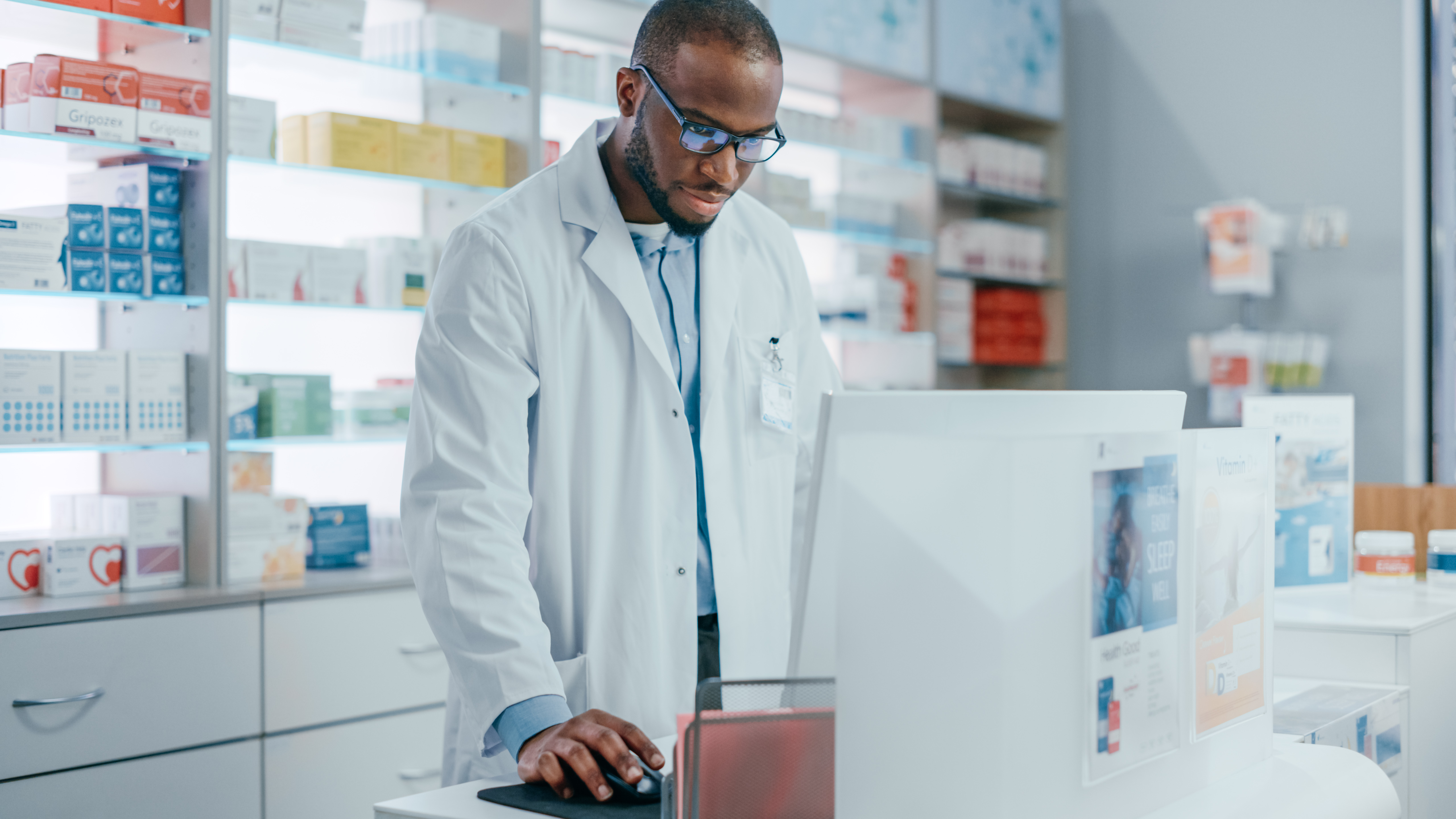 A pharmacist inside a pharmacy looking something up on the computer system.