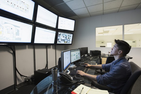 Person on computer looking at multiple screens in a large room.