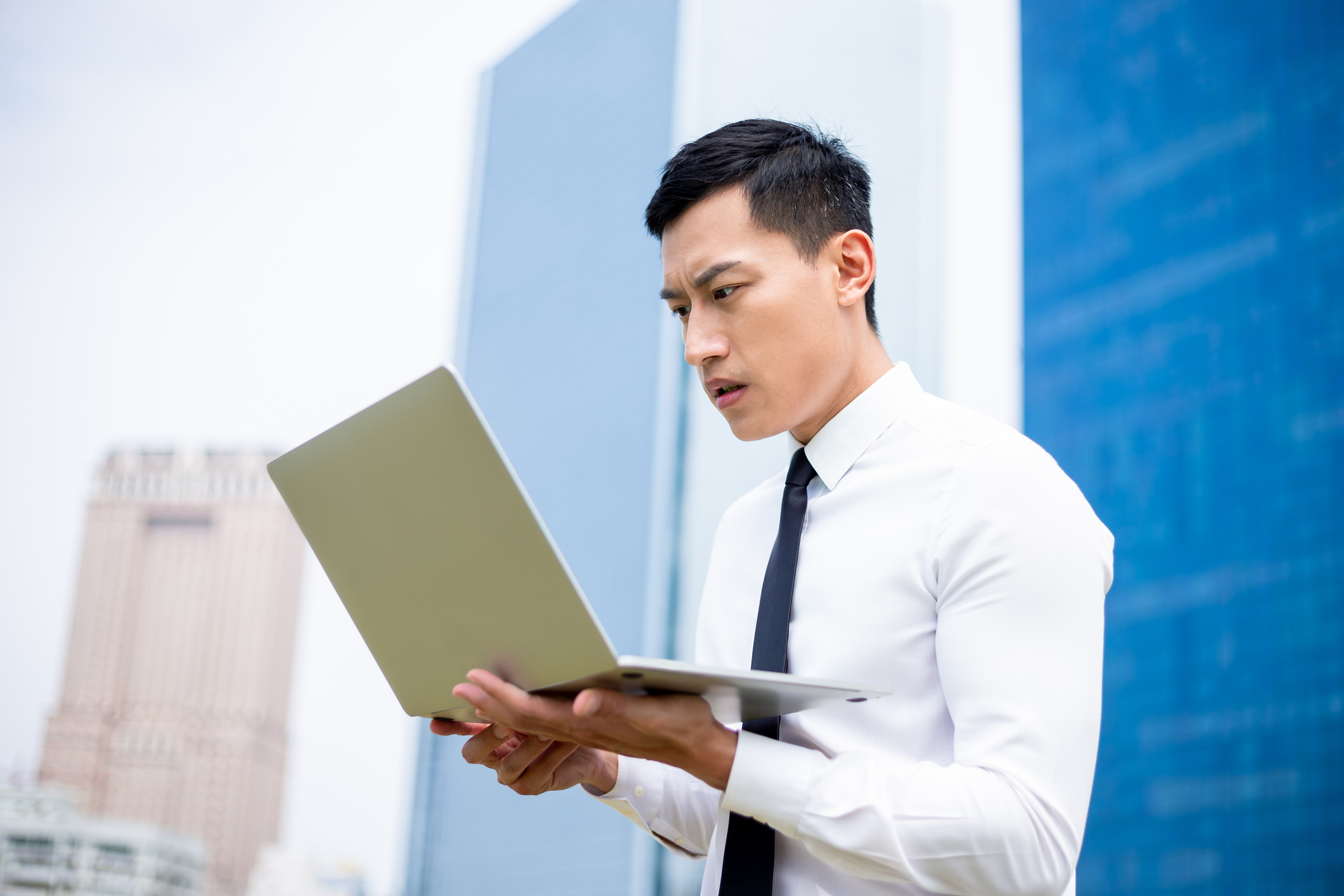 Investor looking at laptop in center of city as stocks decline.
