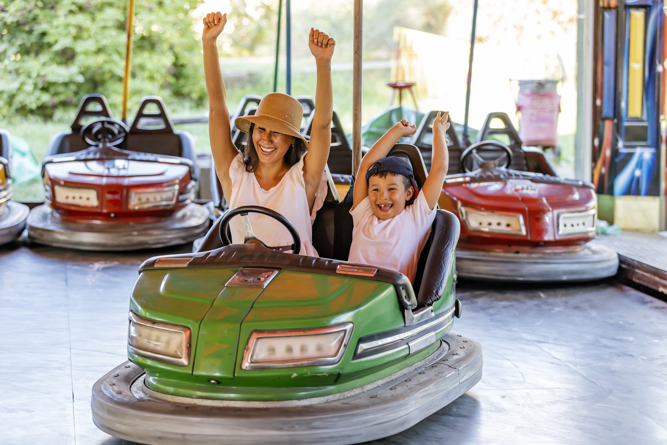 adult and child with arms raised in victory while sitting in a bumper car