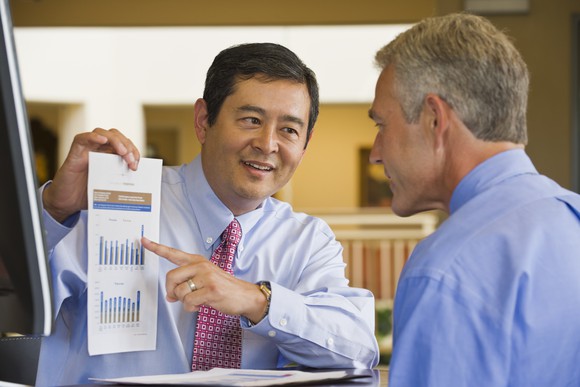 A businessperson explaining data on a graph to another person. 