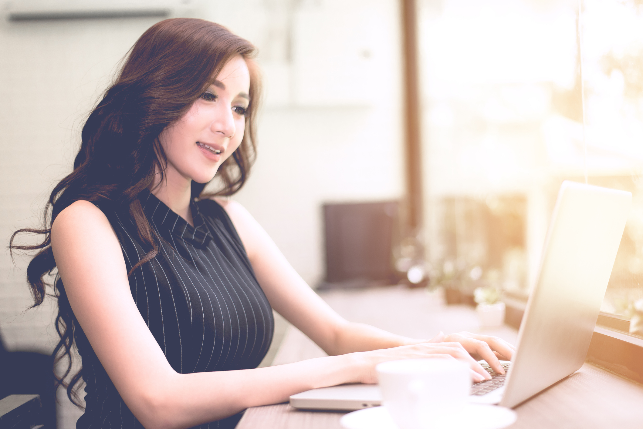 A woman smiling and looking at a laptop.