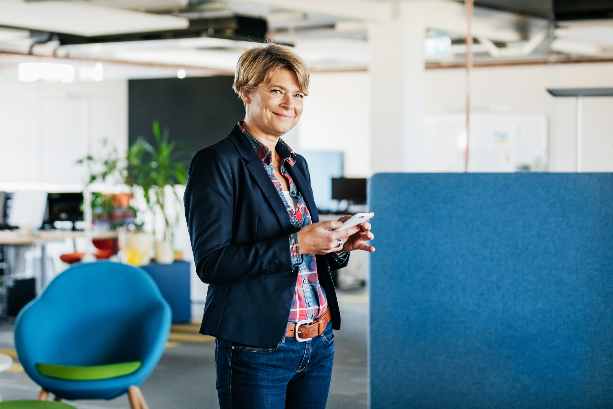 A business person, in an office, smiling and holding a phone.
