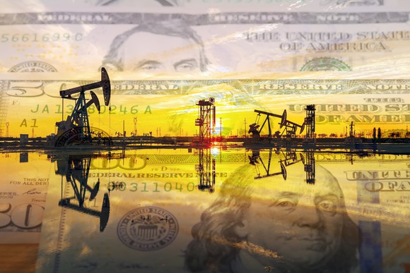 Oil pumps at sunrise with money in the background.