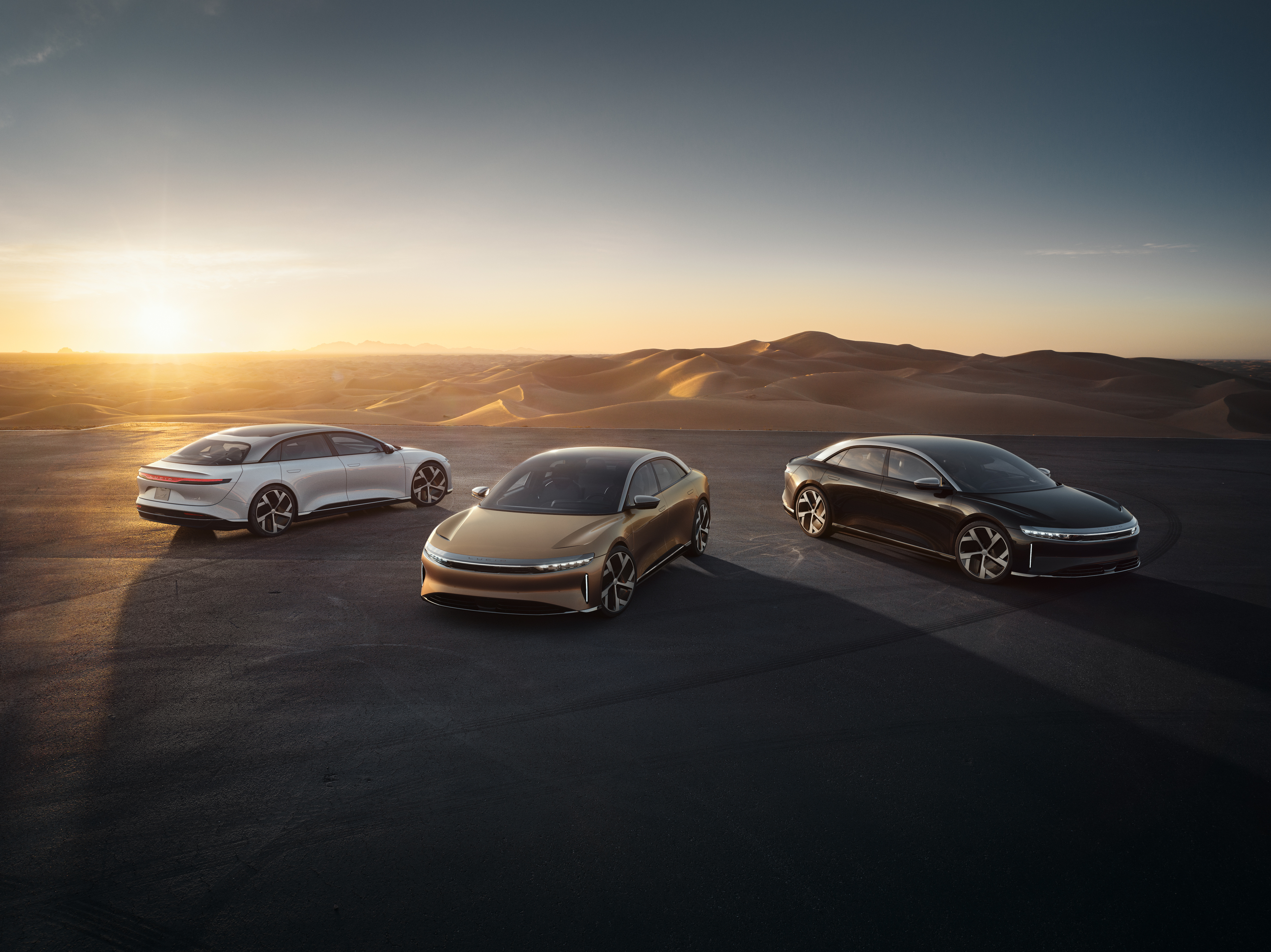 three Lucid Air sedans parked at sunset.